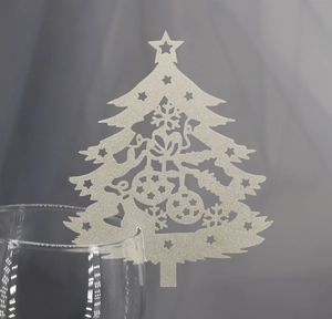 Close-up of laser-cut silver glitter Christmas tree place card on a wine glass rim