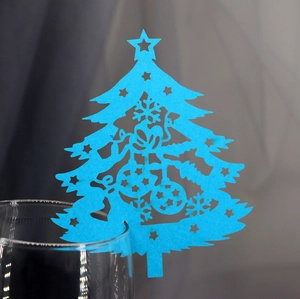Blue laser-cut Christmas tree place card with hollow snowflake design on a wine glass