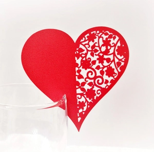 Detail of red heart-shaped laser-cut place card on a wine glass rim for wedding decor