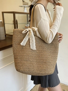 Large straw tote bag with white lace bow and leather straps for beach holidays