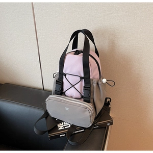 Detail view of pink and gray two-tone backpack with a detachable mini pouch on dark leather