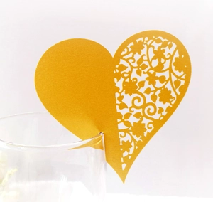 Detailed laser cut heart-shaped place card with intricate floral patterns on a glass rim