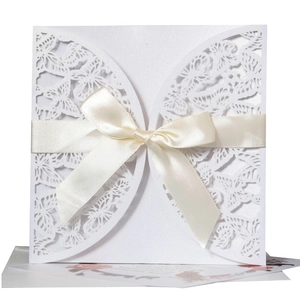Detail of white laser-cut butterfly invitation card with silk ribbon for elegant weddings