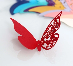 Detail of red laser-cut 3D paper butterfly with intricate hollow floral wing patterns