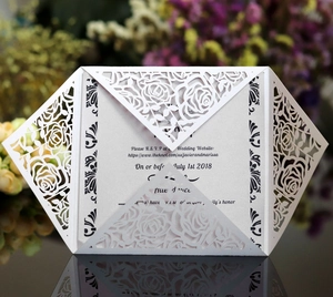 Detail of laser cut white rose wedding invitation with elegant hollowed floral patterns