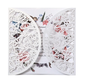Detail of laser-cut white wedding invitation featuring intricate butterfly and floral patterns