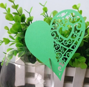 Laser-cut green heart-shaped butterfly place card with floral vine patterns on a glass