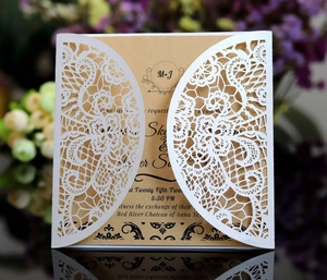Macro view of laser-cut lace invitation with kraft paper insert on a reflective surface