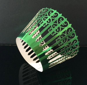 Close-up of green metallic cupcake wrapper with intricate laser-cut vine pattern