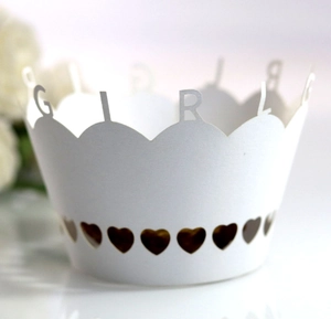 Detail of white laser-cut cupcake wrappers featuring GIRL text and heart hollow patterns