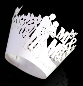 Macro shot of white laser-cut Mr & Mrs cupcake wrapper with intricate floral patterns