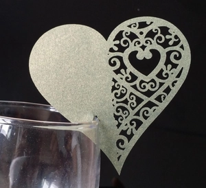 Macro shot of laser-cut champagne gold heart wine glass cards with floral pattern