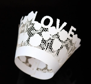 Detail of white laser-cut lace cupcake wrapper with LOVE lettering and honeycomb pattern