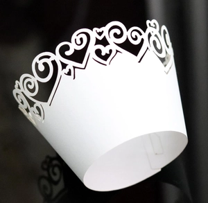 Detail of white laser cut heart hollow cupcake wrapper with elegant vine pattern