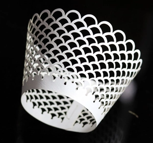 Macro detail of laser-cut white cupcake wrapper with elegant fish scale hollow pattern