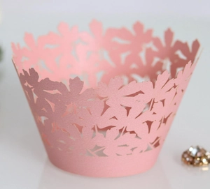 Macro detail of laser-cut flower lace pattern on pink pearlescent paper cupcake wrapper