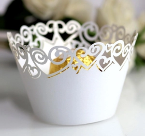 Close-up of white laser-cut cupcake wrapper with hollow heart patterns for weddings
