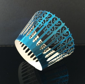 Detail of laser-cut lake blue cupcake wrapper with decorative floral vine patterns