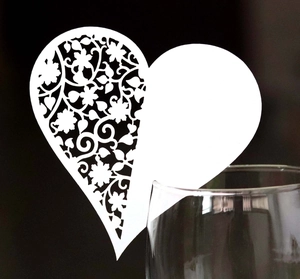 White laser-cut heart paper place card with floral details for wedding wine glasses