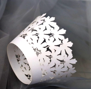 Close-up of laser-cut white cupcake wrapper with intricate leaf pattern decoration