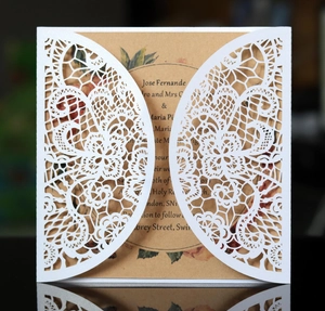 Detail of laser-cut lace floral pattern on white card with kraft paper insert