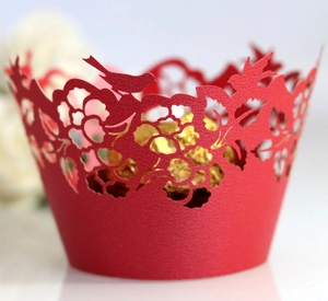 Laser-cut red cupcake wrappers with intricate floral patterns and bird silhouette design
