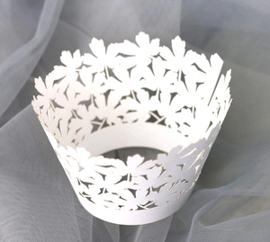 Detailed laser-cut white cupcake wrapper featuring elegant hollow leaf patterns
