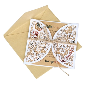 Detail of laser cut white lace invitation with kraft paper card and natural jute twine