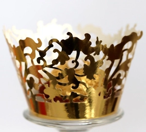 Close-up of golden laser-cut lace cupcake wrapper with intricate floral vine patterns
