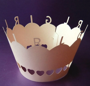 Detailed view of pink laser-cut paper cupcake wrapper with GIRL lettering and hearts
