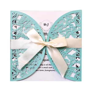 Macro detail of laser-cut butterfly wedding invitation with cream satin ribbon bow