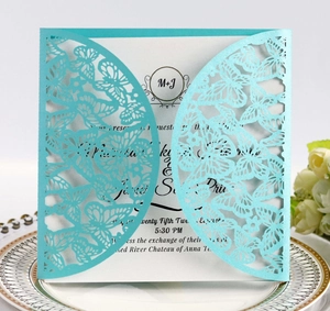 Macro shot of laser-cut light blue butterfly invitation on white porcelain plate