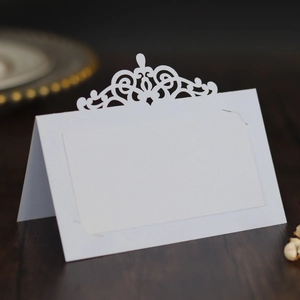Détail de couronne découpée au laser sur un marque-place blanc perlé pour mariage