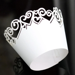 White laser-cut cupcake wrappers with heart scroll pattern for elegant party decoration
