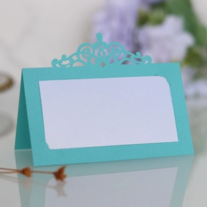 Détail du marque-place bleu lac avec découpe laser couronne et insert blanc pour mariages
