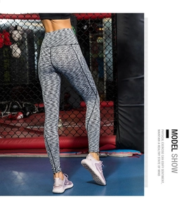 Dettaglio dei leggings yoga grigi a vita alta con cuciture snellenti in un contesto fitness