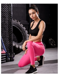 Detail of pink high-waist yoga leggings and black sports bra in industrial gym setting