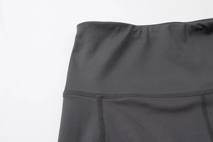 Detail of high-waist yoga shorts showing professional flatlock stitching and grey fabric