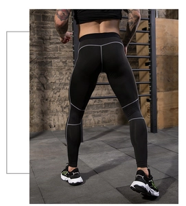 Close-up of men's compression pants with gray stitching in an industrial gym setting