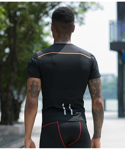 Rear view of black compression gym shirt showing reflective tabs and orange back stripe