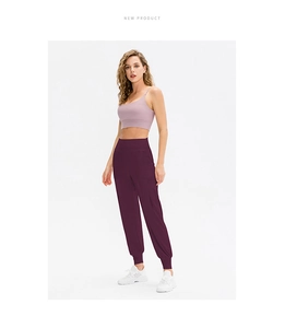 Damen Yoga-Jogginghose in Dunkelrot mit lila Sport-BH und weißen Sportschuhen