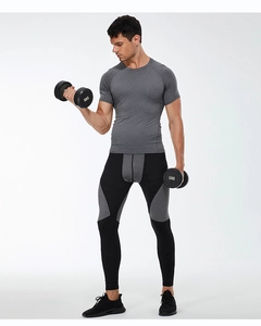Male athlete in grey quick-dry t-shirt and compression pants holding a dumbbell