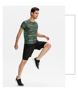 Vue latérale d'un homme courant en t-shirt de sport camouflage et short noir
