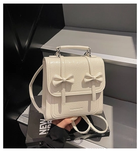 Close-up of cream-colored backpack featuring bow accents and vintage wrinkled texture