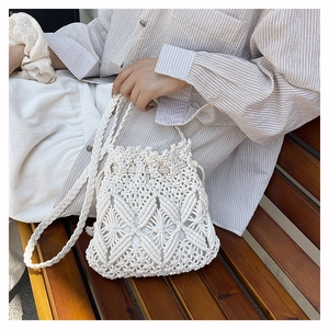 Detail of white handmade macramé bucket bag featuring intricate hollow diamond weave patterns