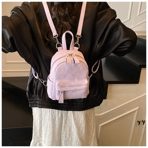 Detail of lavender snake-embossed mini backpack with silver hardware on a model
