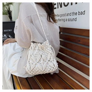 Detail of white crochet hollow bucket bag with woven shoulder strap for beach holidays