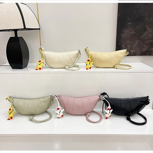 Detail of five croissant crescent bags in lychee leather with cute duck charms