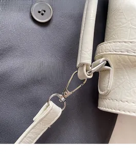 Detailed macro view of white pleated leather bag with shiny silver metal hardware hooks