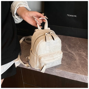 Detail of cream mini backpack with faux snakeskin texture and metal zipper pockets